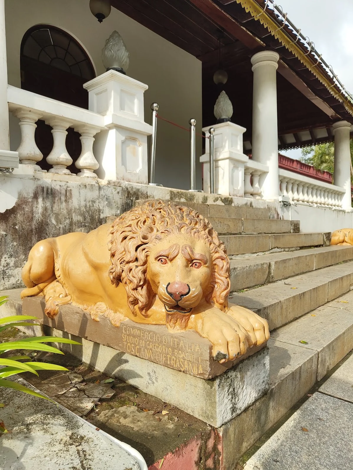Gold-painted marble lion sculpture at palace steps in Trivandrum, with the same Pietrasanta inscription visible on the base