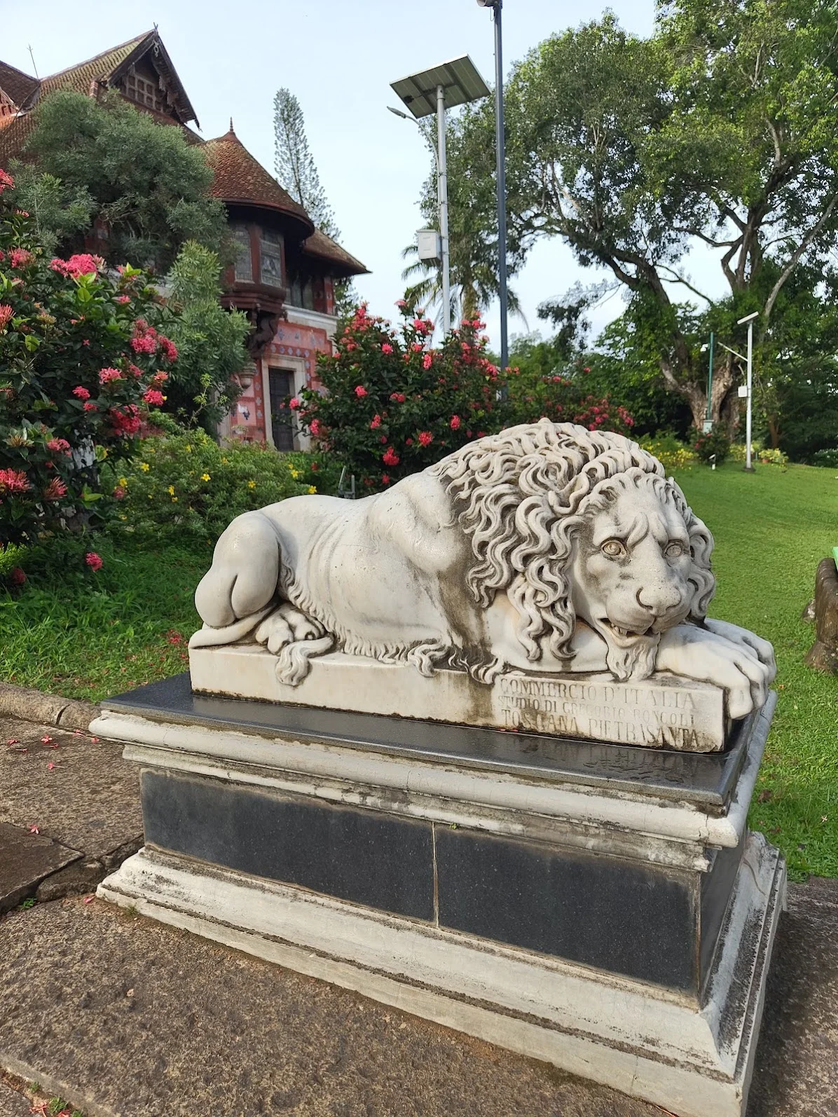 Side view of white marble lion sculpture at Kanakakunnu Palace showing the detailed curling mane and amber eyes